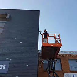 Painter on a boom lift painting a commercial facade
