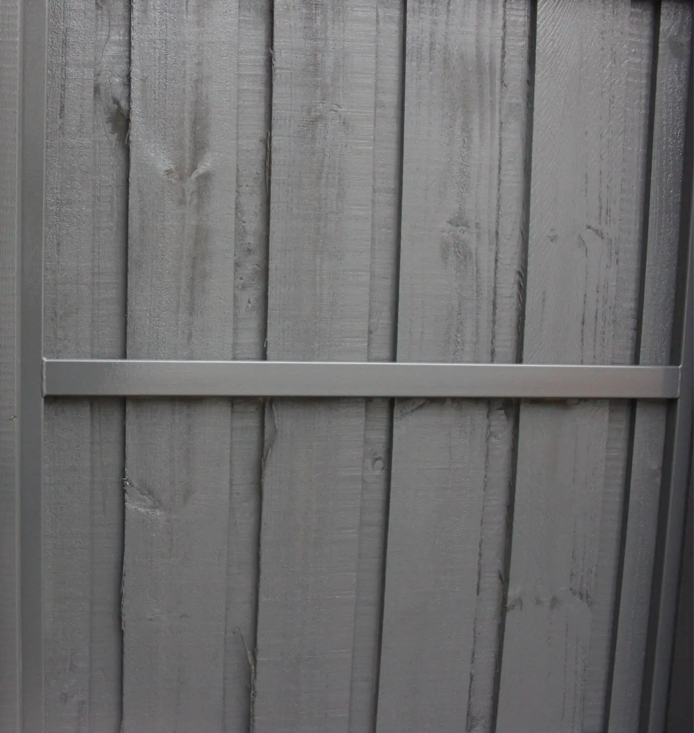 Close-up of deep charcoal paint on rough-sawn fence palings