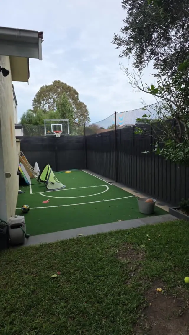Dark grey fence around a backyard basketball court